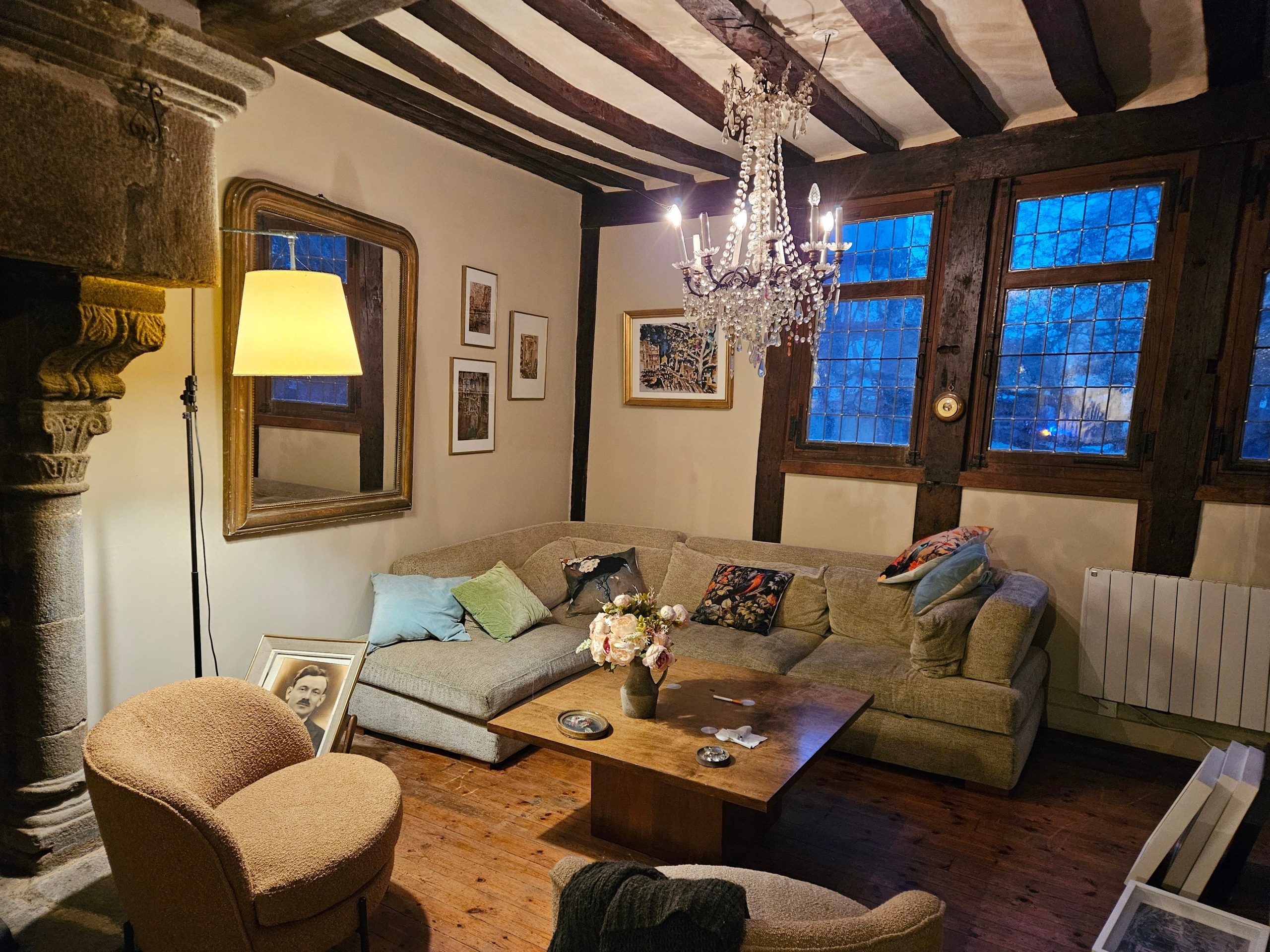 Au premier étage, une vaste pièce de vie donne le ton : poutres apparentes, cheminée classée, vitraux colorés et mobilier design composent un décor à la fois accueillant et fonctionnel.