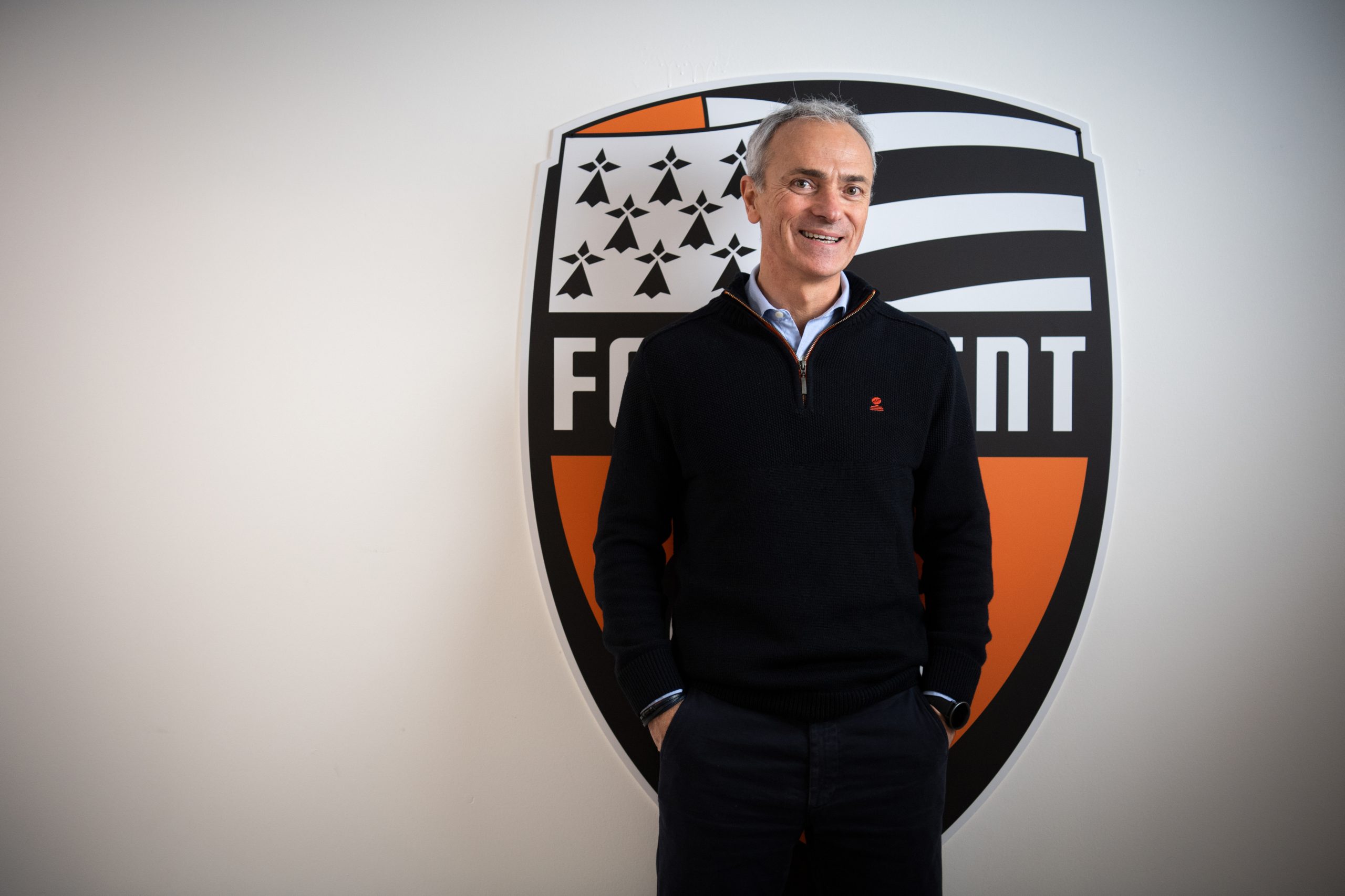 Arnaud Tanguy posant devant le logo du FC Lorient.